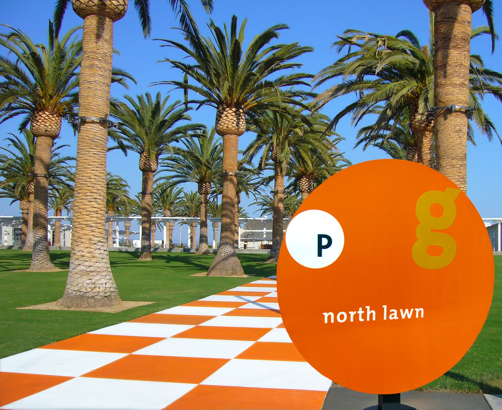 North lawn, palm trees and orange wayfinding sign at the City of Irvine Great Park.